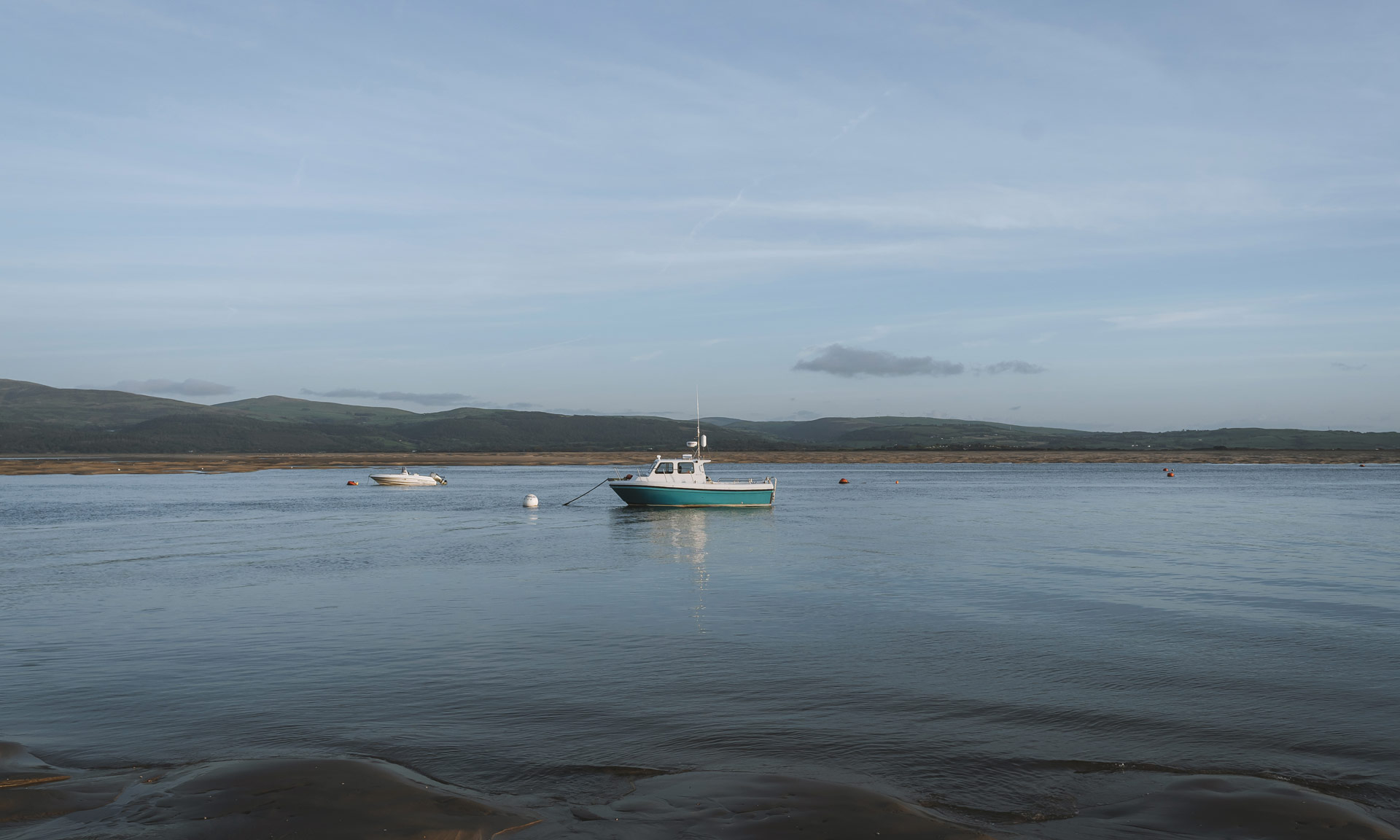 A boat floats in the calm waters of Aberdyfi