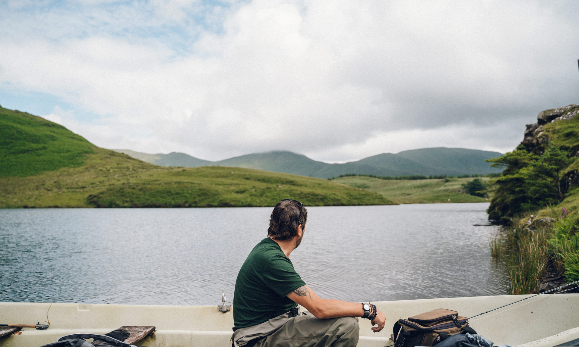 Fisherman looks over Llyn Dywarchen from his boat