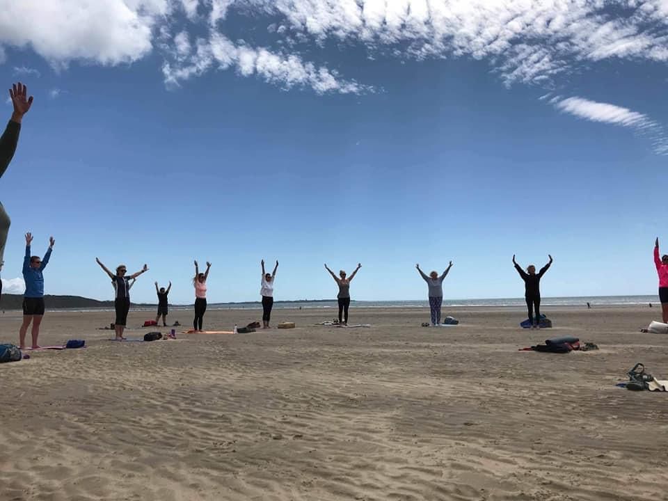 An outdoor yoga session taking place on a beach on a sunny day